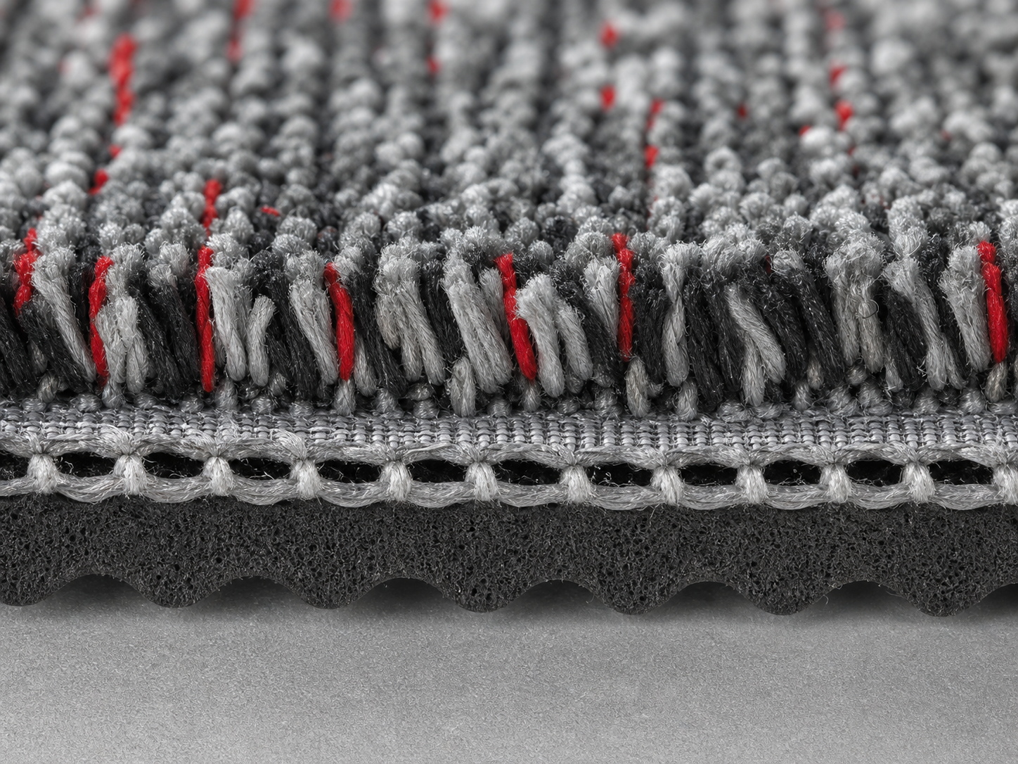 Close-up cross section of bonded carpet fibers and backing